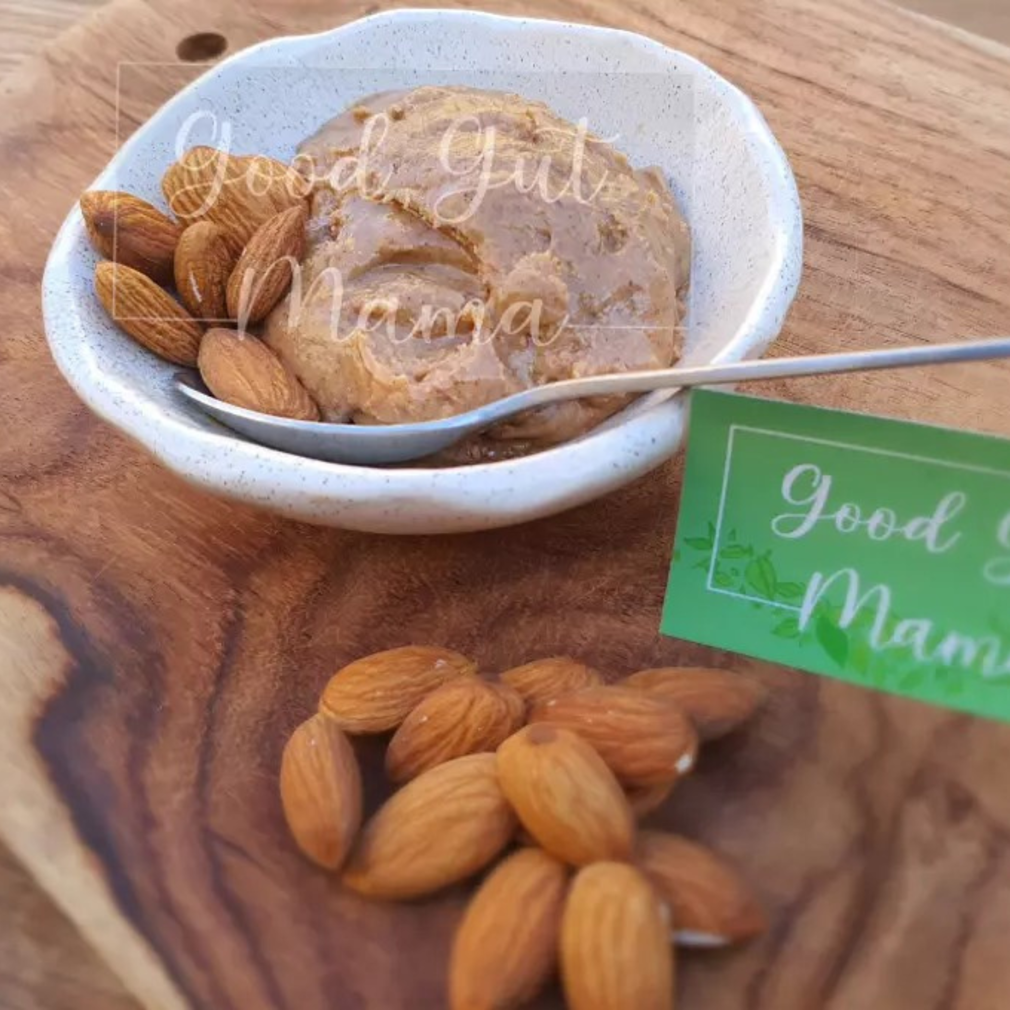 Almond Butter from Good Gut Mama, available at Elmeraki, displayed in a jar with a spoon and almonds.