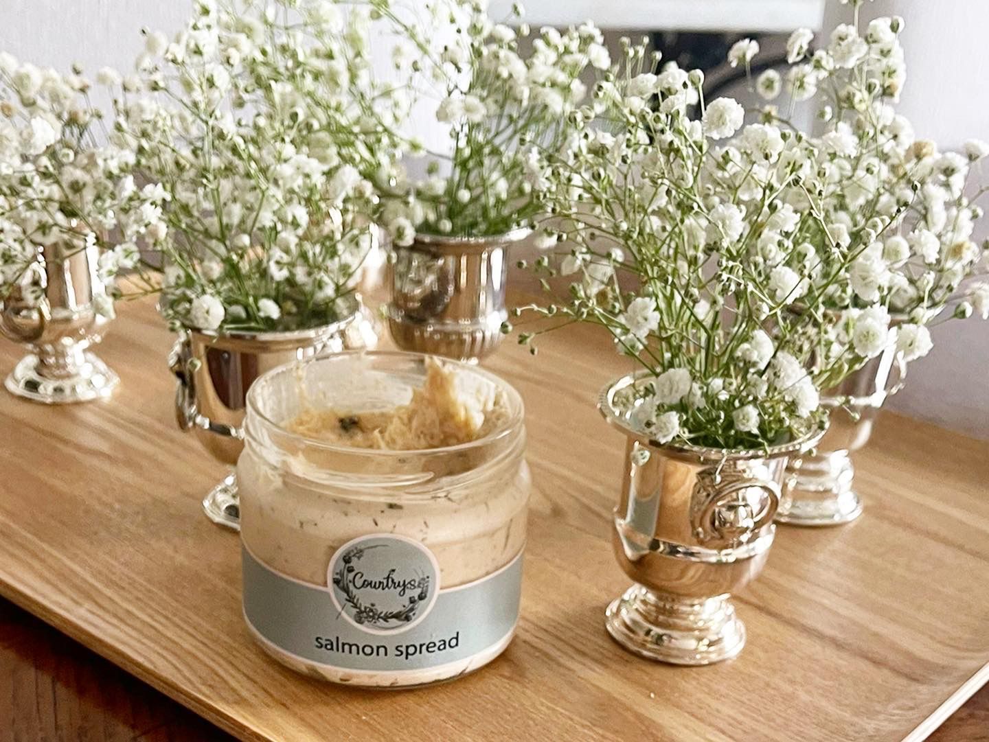 Glass jar of Country's creamy Salmon Spread with a spoon, from El Meraki store.