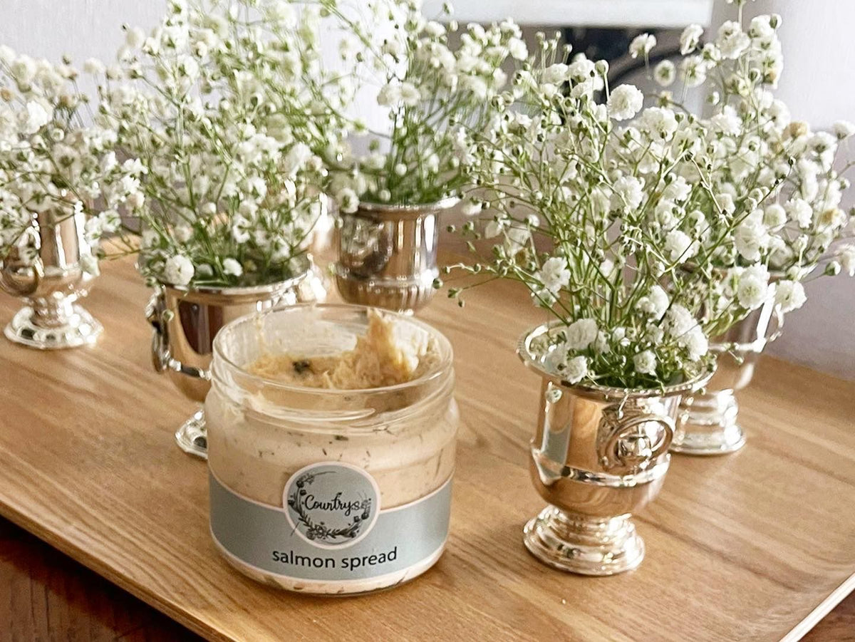 Glass jar of Country's creamy Salmon Spread with a spoon, from El Meraki store.