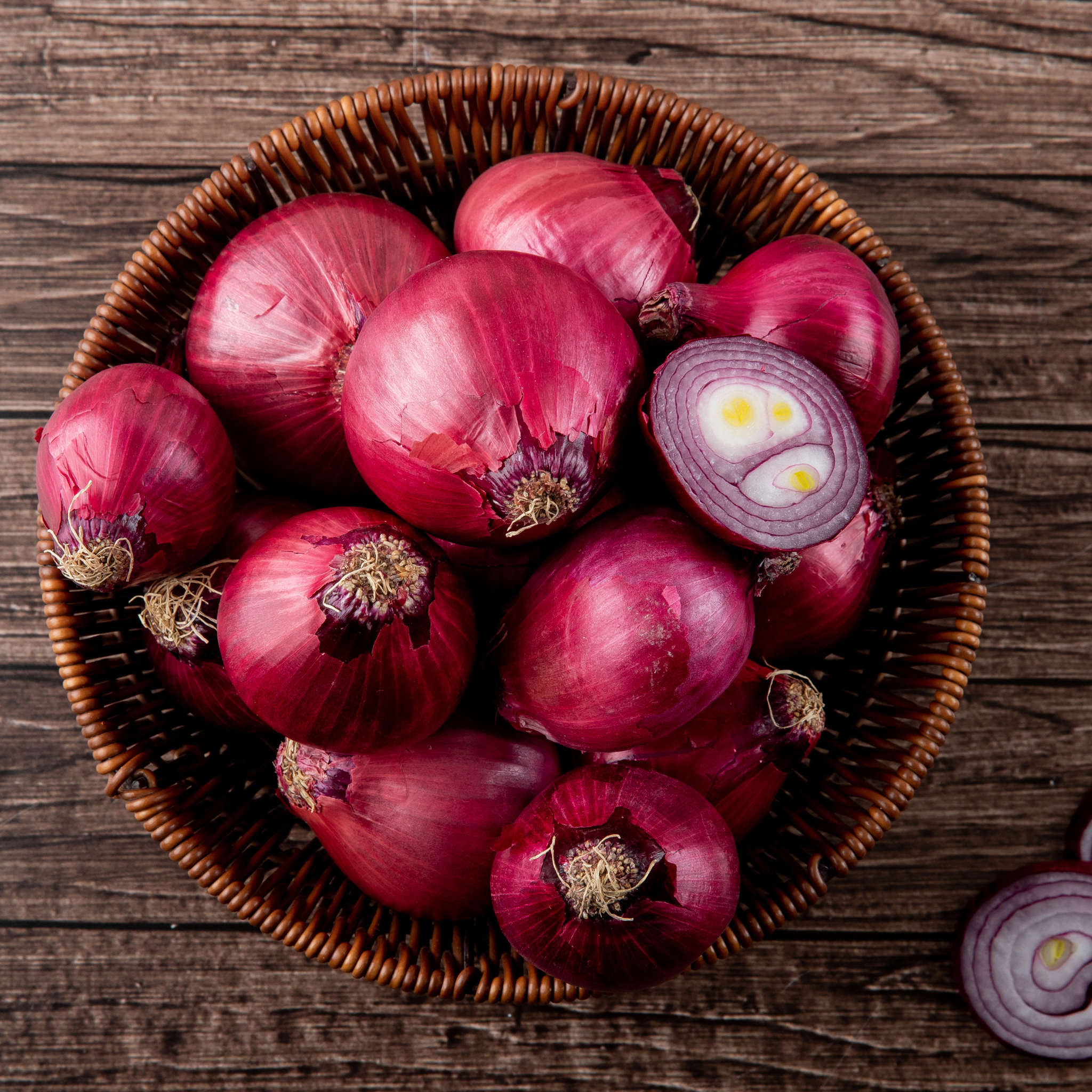 Fresh, whole red onions from El Kitchen Garden, showcasing their vibrant purple skin and white interior.
