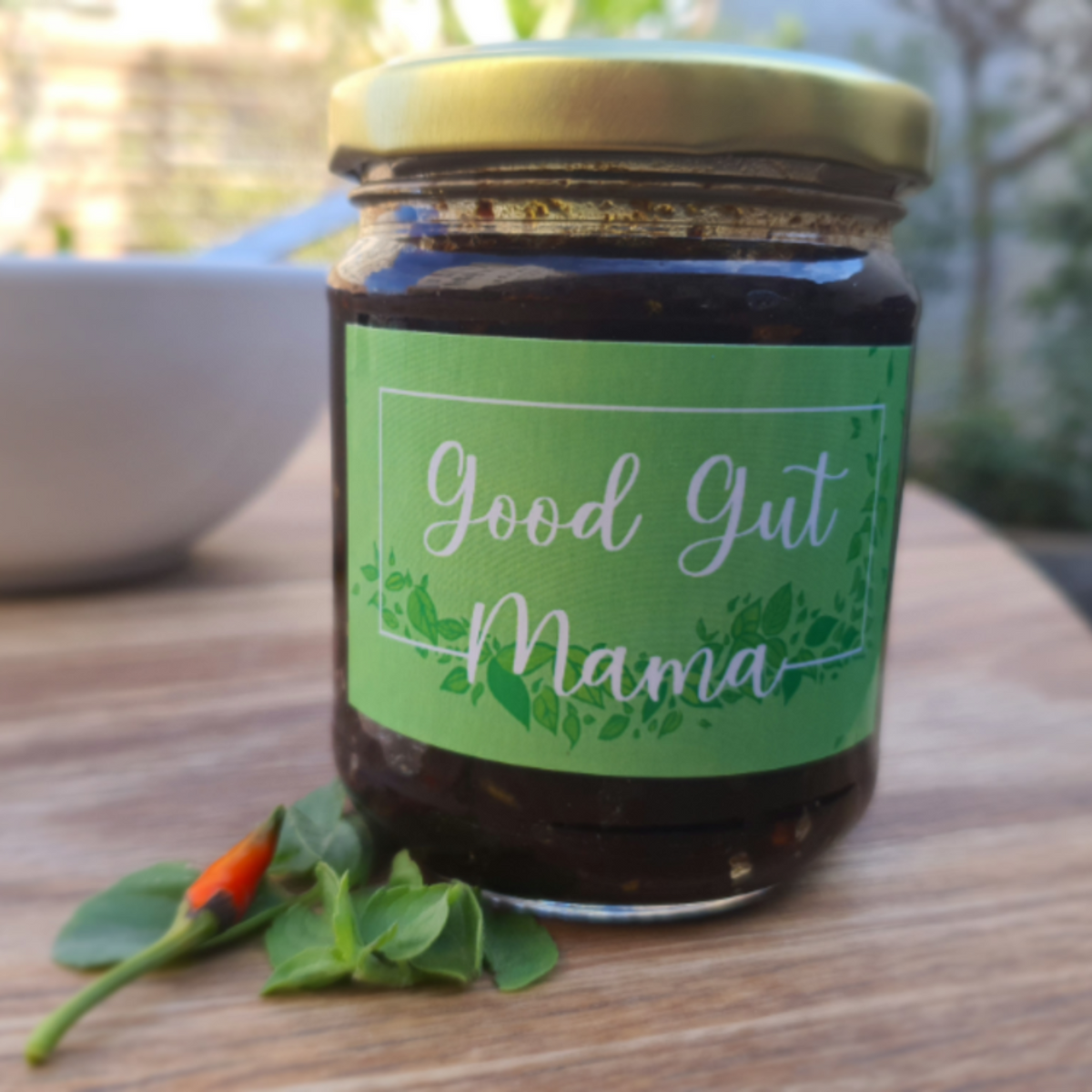 Nam Prik Pao (Thai Chilli Jam) from Good Gut Mama, available at Elmeraki, displayed in a jar with fresh chili peppers and herbs.